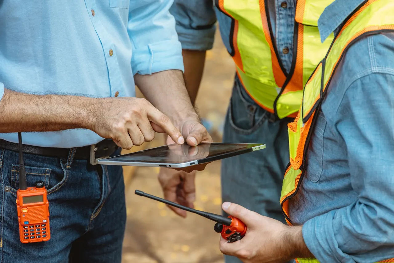Two site managers reviewing issue data on a tablet to spot recurring defect trends
