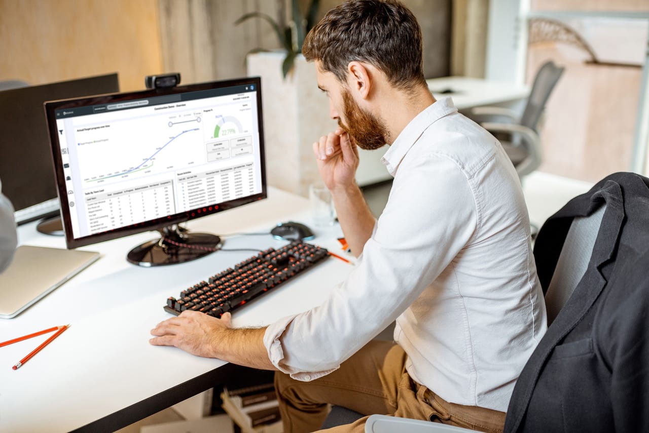 Project manager reviewing an RDrive progress analytics chart on a desktop monitor to keep delivery on track