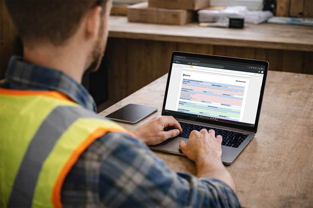 Site supervisor filling in an RDrive risk assessment register on a laptop at a site desk