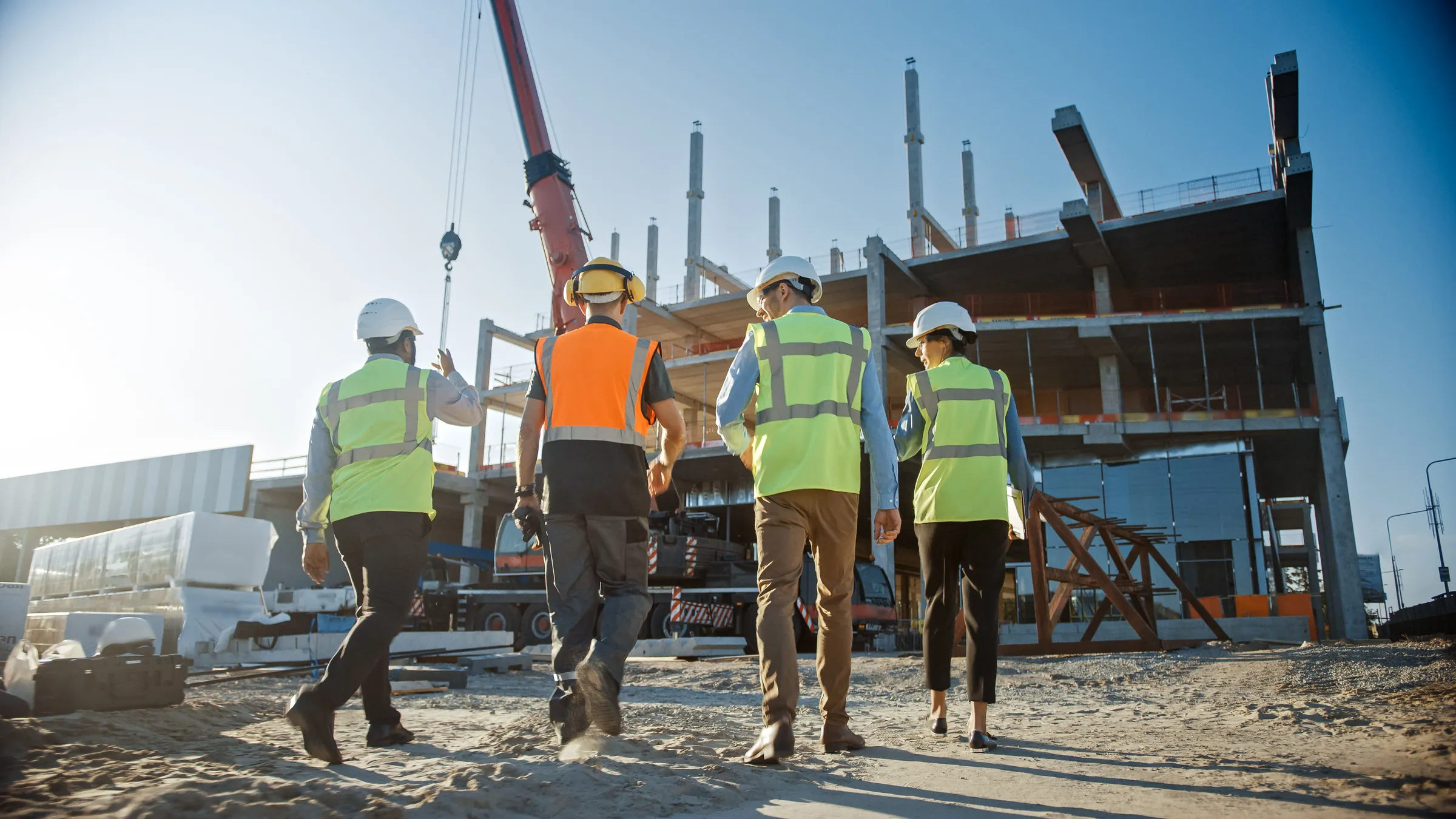 Site team in hi-vis walking towards a building under construction, ready to capture field data