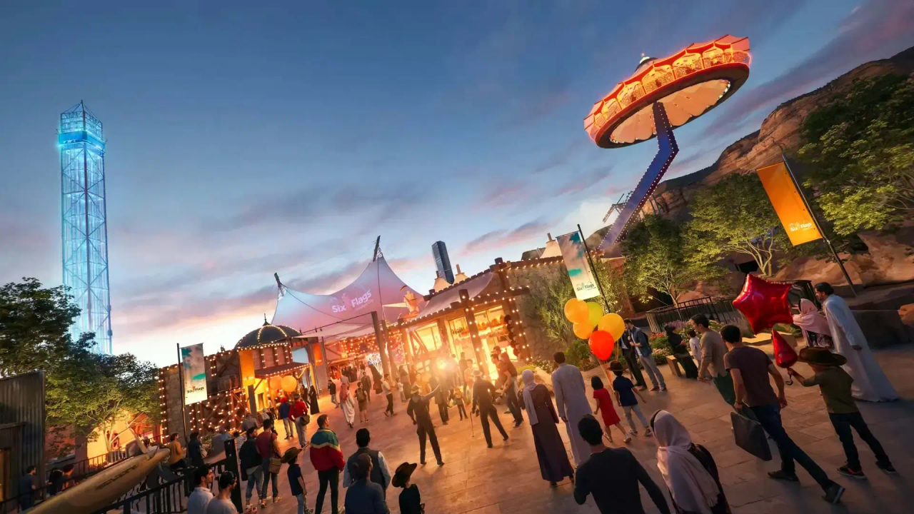 Dusk view of the Valley of Fortune area at Six Flags Qiddiya with visitors and rides